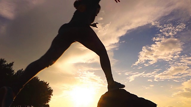 年轻的徒步旅行者在日落时从岩石上跳下来，慢镜头视频素材