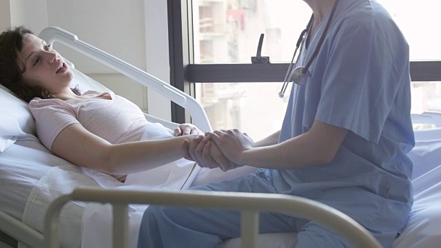 男护士扶着病人的手安慰她躺在病床上视频素材