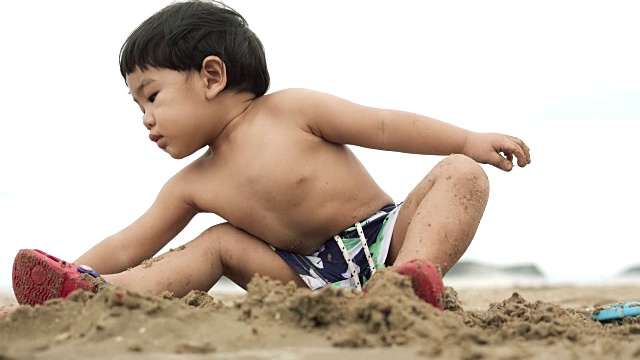 小男孩在沙滩上玩沙子玩具视频素材