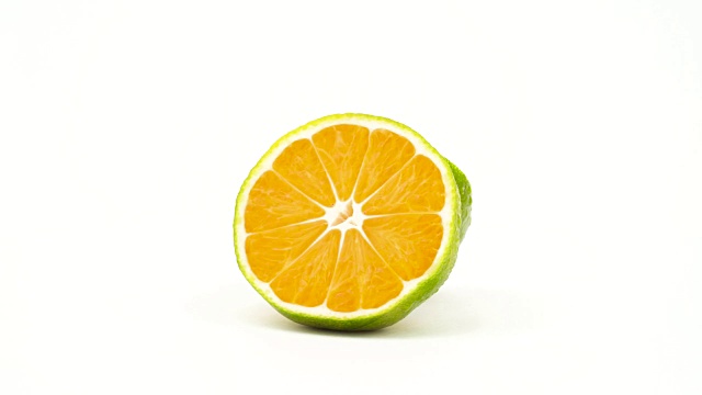 两个半瓣的绿橘子，带有水滴。在转盘上旋转。孤立在白色背景上。特写镜头。宏。视频下载