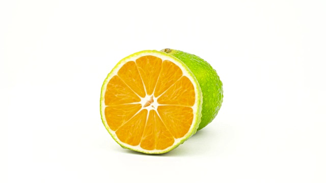 一个完整的和一半切的绿色的橘子和水滴。在转盘上旋转。孤立在白色背景上。特写镜头。宏。视频下载