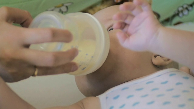 特写:母亲用奶瓶喂新生婴儿。视频素材