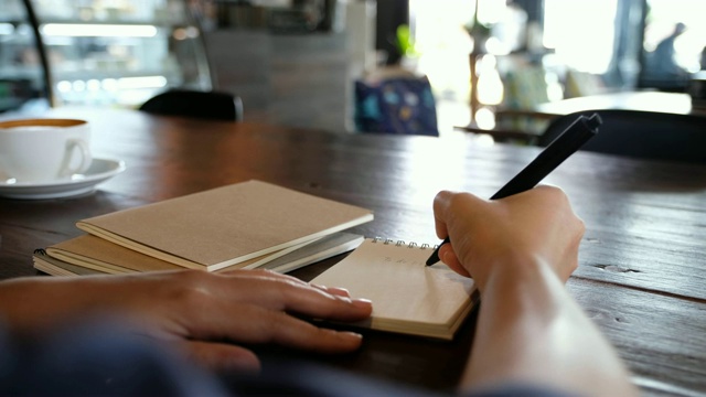 一只手写在桌上的空白笔记本上视频素材