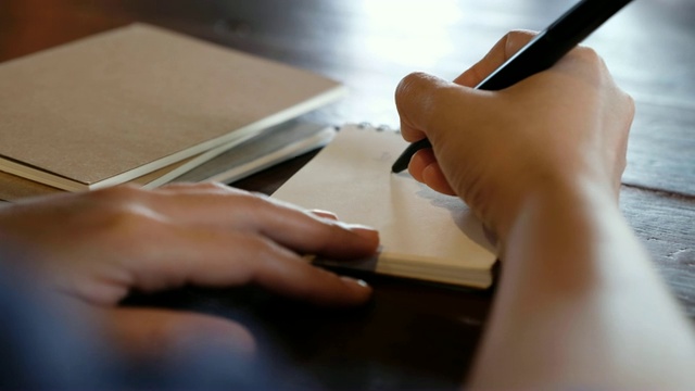 一只手写在桌上的空白笔记本上视频素材