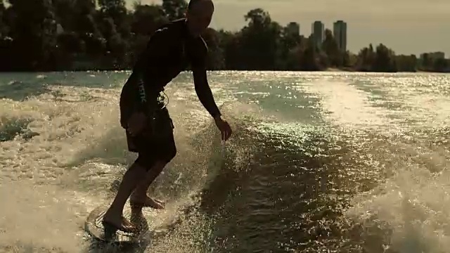 Wake冲浪者喜欢晚上的波浪。在日落时冲浪的骑手的特写视频素材