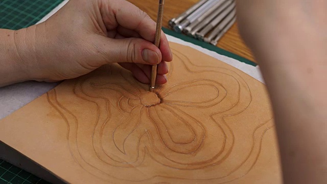 工匠用斜角冲压工具在皮革上冲压花的图纸视频素材