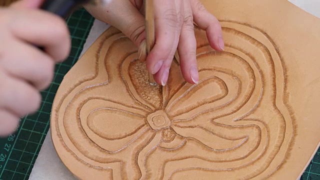 工匠用背景冲压工具和木槌把花印在皮革上视频素材