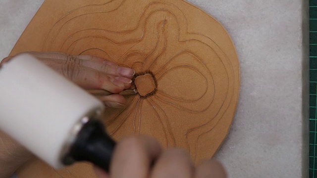 工匠用斜角冲压工具和木槌在皮革上刻花视频素材