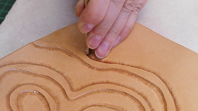 工匠用斜角冲压工具在皮革表面上冲压装饰品视频素材