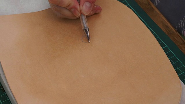 工匠在雕刻前画出皮革的形状来绘制图案视频下载