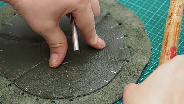 工匠用打孔和锤在缝制的袋上打孔视频下载