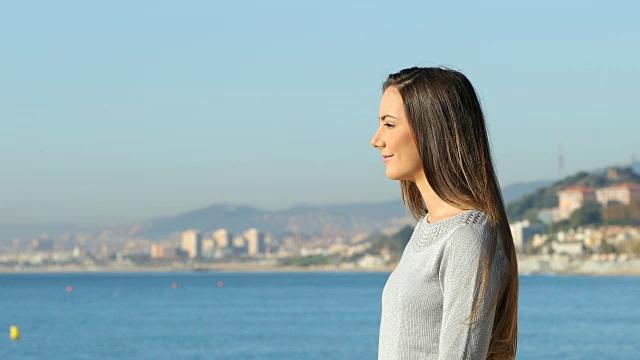一个女人在海滩上呼吸微笑的侧面视频素材