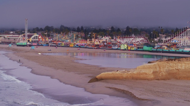 海浪拍击海滩附近的圣克鲁斯木板路在日出-无人机拍摄视频素材