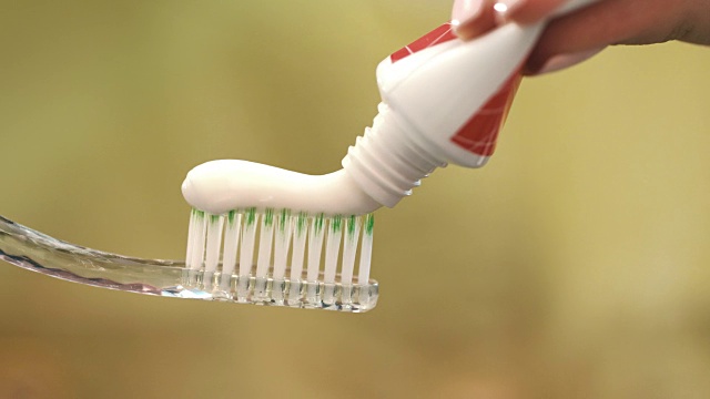 白色牙膏挤在牙刷上。手持牙刷的女人视频下载