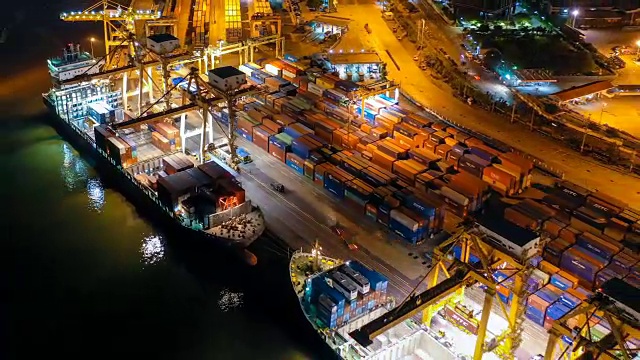 鸟瞰图无人机延时或延时拍摄的工业港口或造船厂与集装箱船在晚上在东南亚视频素材