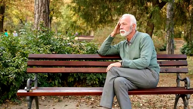 一个老人独自坐在公园的长椅上视频下载