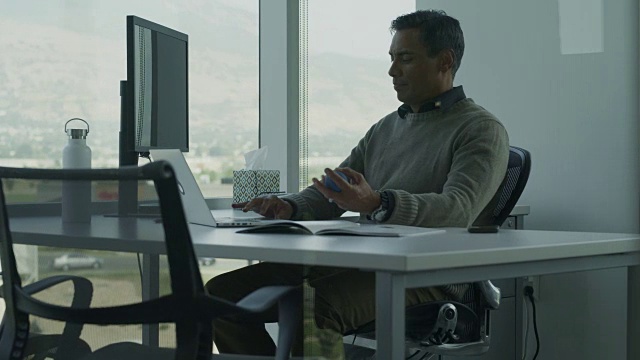 商人在办公室用笔记本电脑打字和挤压压力球的镜头/美国犹他州的Pleasant Grove视频素材