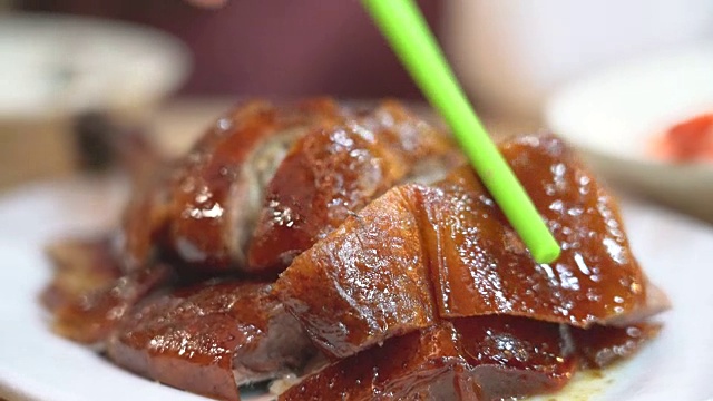 在香港的一家香港餐厅里，一只手拿着筷子，从盘子里拿一块烤鸭，视频下载