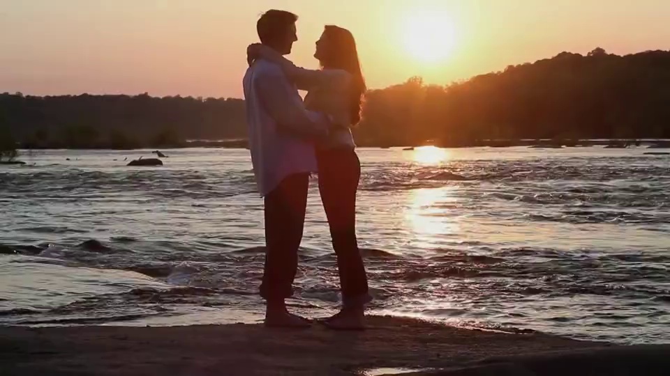 日落时分，在河边手拉手拥抱的夫妇/里士满，弗吉尼亚，美国视频下载