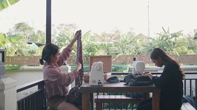 两个亚洲女裁缝一起在缝纫机上工作。视频素材