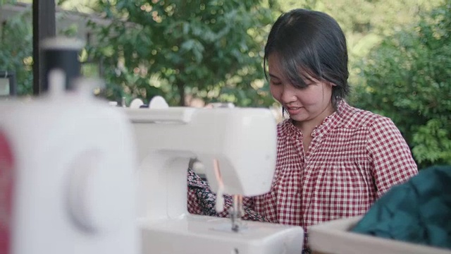 年轻的亚洲女裁缝在缝纫机上工作。视频素材