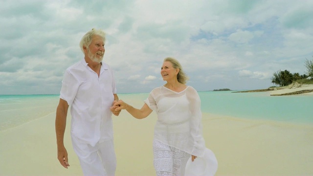 退休老两口幸福地一起漫步热带海滩视频下载