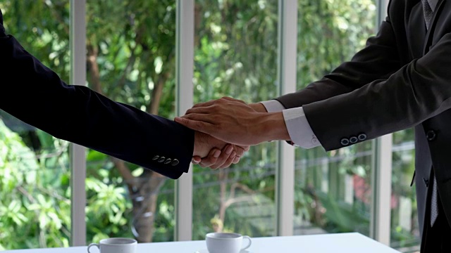 两个亚洲商人合作伙伴握手在办公室背景，业务概念，有利可图的协议，合作视频素材