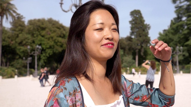 微笑轻松的年轻中国女子在公园慢动作视频素材