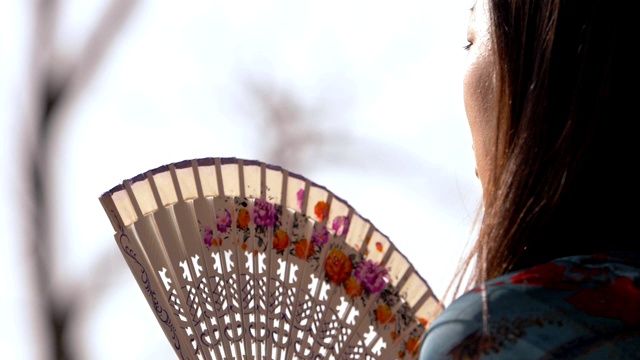 一名中国女子在公园挥动扇子。热,summer-slow运动视频下载