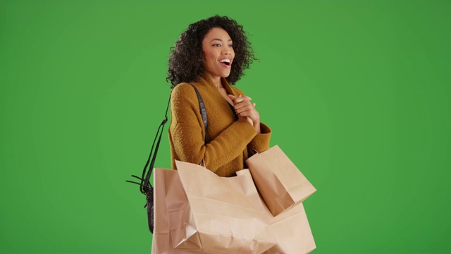 时尚的黑人妇女购物袋看到她喜欢的东西在绿色屏幕上视频购买