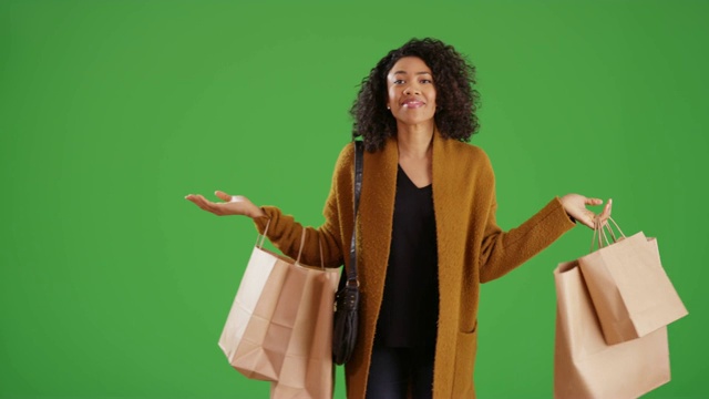 快乐时尚的黑人妇女在绿色屏幕上拿着购物袋纺纱视频素材
