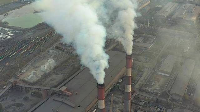 工业园区有一根红白相间的大管子，浓浓的白烟从工厂的管子里倾泻出来，与太阳形成对比。鸟瞰图视频素材