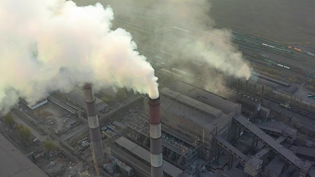 工业园区有一根红白相间的大管子，浓浓的白烟从工厂的管子里倾泻出来，与太阳形成对比。鸟瞰图视频素材