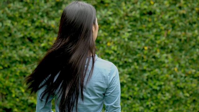 近距离观看美丽年轻的亚洲女子在花园中漫步，女孩独自在外感受公园里的寂寞，生活理念，慢镜头。视频下载