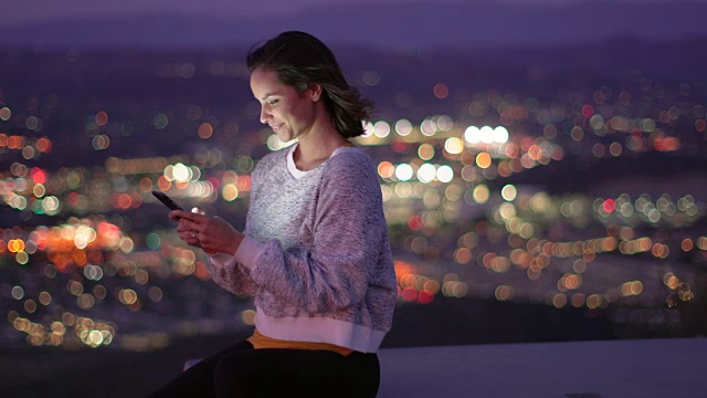 一个年轻女子在晚上使用手机视频素材