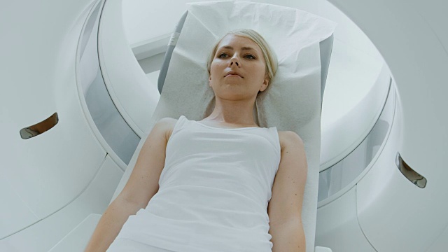 在医学实验室男性放射学家控制MRI或CT或PET扫描与女性病人进行程序。高科技现代医疗设备。提升相机拍摄。视频素材