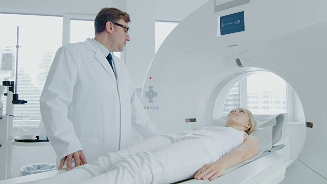 在医学实验室男性放射科控制MRI或CT扫描与女性患者进行程序。高科技现代医疗设备。提升相机拍摄。视频素材