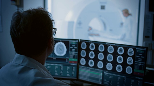 在医学实验室，病人在放射科医生的监督下接受MRI或CT扫描过程，在控制室，医生观察过程并监测大脑扫描结果。视频素材