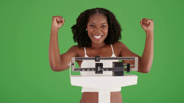 一位黑人女性达到了她的体重目标，看着镜头，在绿色屏幕上欢呼视频下载