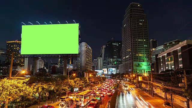 时间推移:夜间有绿色屏幕和城市交通灯背景的广告牌。4 k决议。视频素材