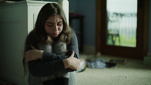 用摇盘拍摄的沮丧女孩坐在地板上哭泣/犹他州雪松山，美国视频下载