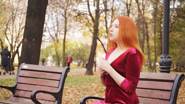 一个小女孩坐在公园的长椅上，等着电话视频素材