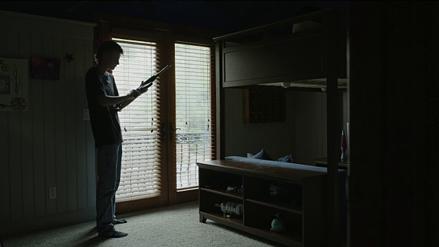 美国犹他州雪松山，一名年轻人在卧室练习AR-15步枪的瞄准和射击视频下载