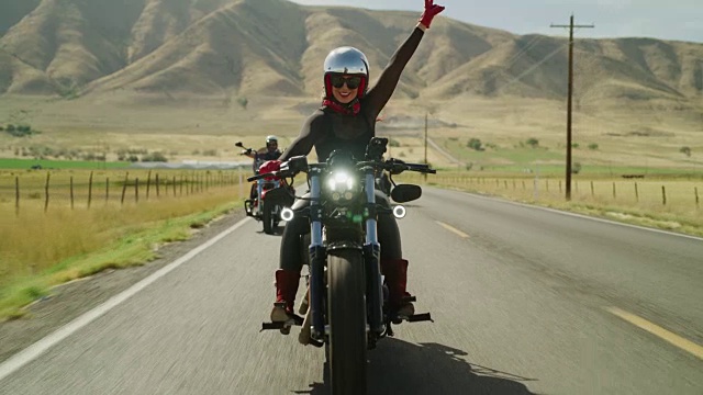 妇女骑摩托车在偏远的道路上举起手臂的慢动作/佩森，犹他州，美国视频下载
