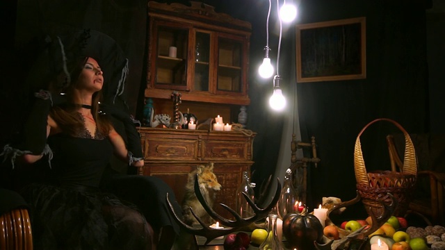 万圣节女巫在椅子上摇摆，并整理她的帽子。视频素材