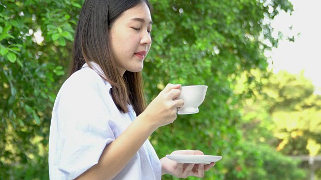 4 k;亚洲女人早上在阳台喝热饮。视频素材