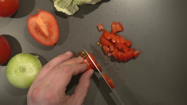 男子正在切新鲜的有机番茄做素食菜肴视频素材
