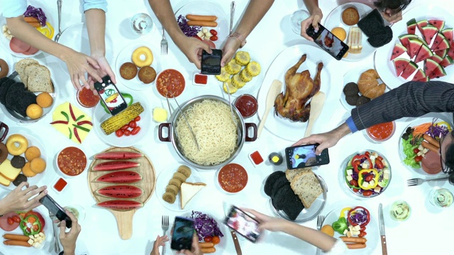 一起吃饭的俯视图。人们用智能手机拍照与餐桌上的食物。节日的概念、生日、新年快乐、圣诞快乐。4 k决议。视频下载