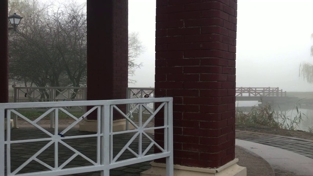 湖上休憩的凉亭。附近有一座木桥。周围的一切都笼罩在浓雾之中。视频素材