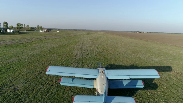 春天，一架蓝色的飞机在天空和地平线的映衬下飞过田野视频下载